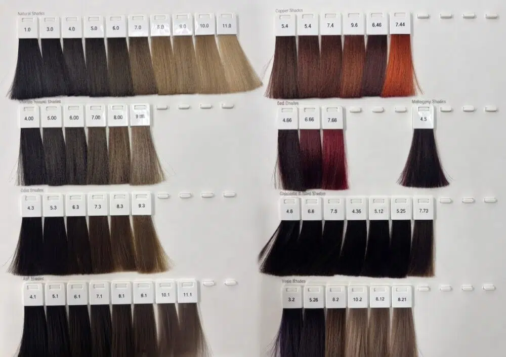 Salon color chart showing numerous hair color samples organized by shade families (natural, copper, red, ash, etc.) with numeric codes above each strand.