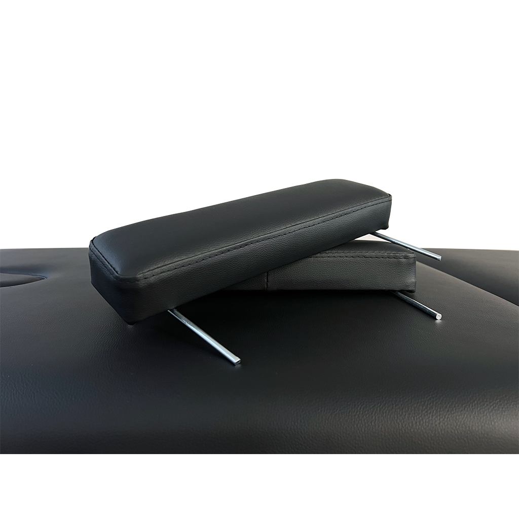 Arm_Restspng – Rapple Pair of black padded cushions with metal support rods resting on a dark leather surface; looks like portable headrest or armrest cushions.
