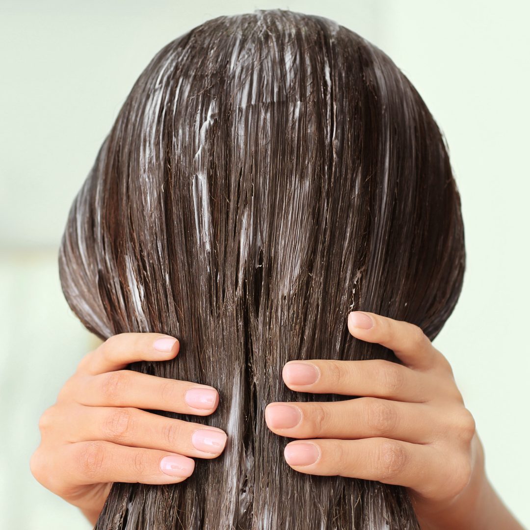 Hands working a treatment through hair