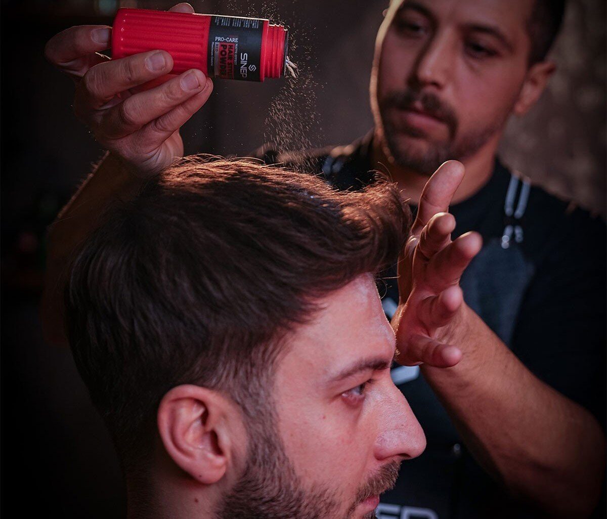 Barber sprinkling SINEP styling powder onto a client's hair