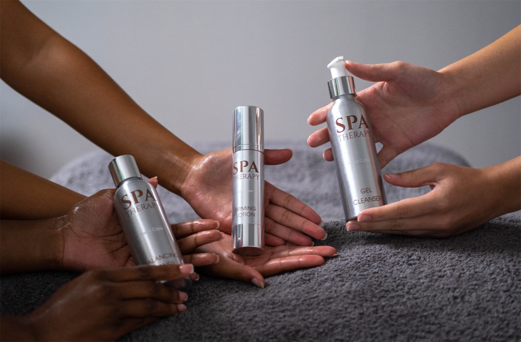 Therapists' hands holding Spa Therapy bottles